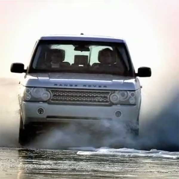 A white Range Rover driving through water features in a film for a range Rover Dealer Experience event.